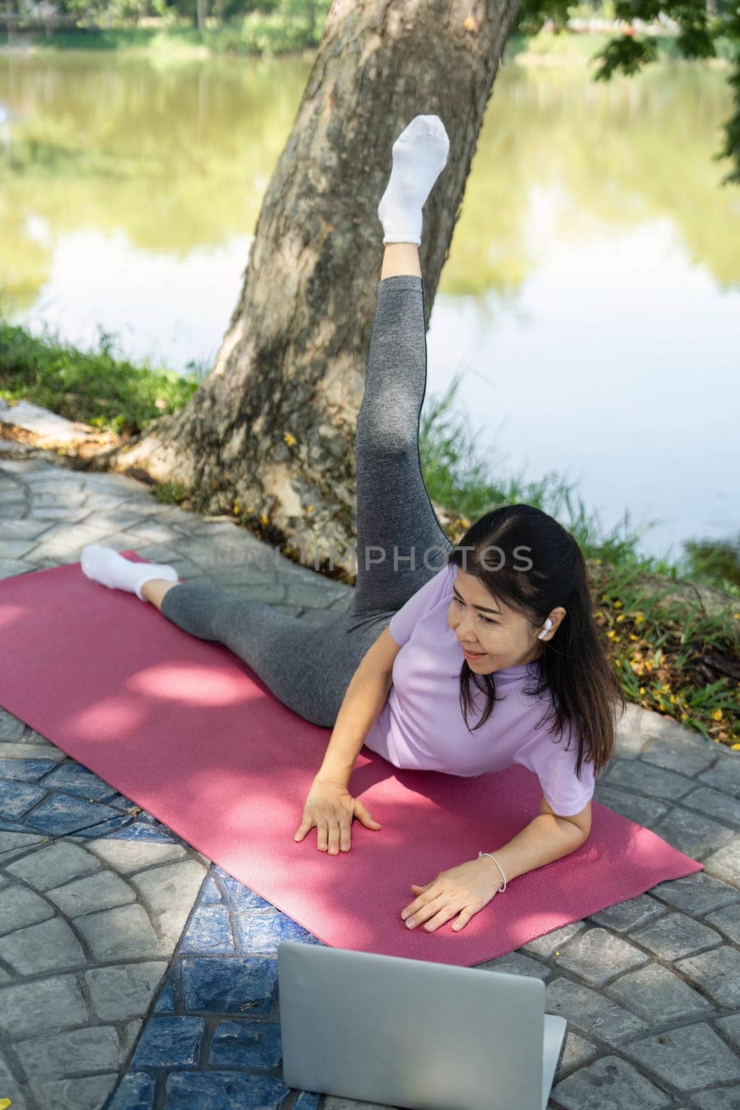 A woman performs a yoga stretch on a mat near a serene lake, promoting wellness and mindfulness in nature.