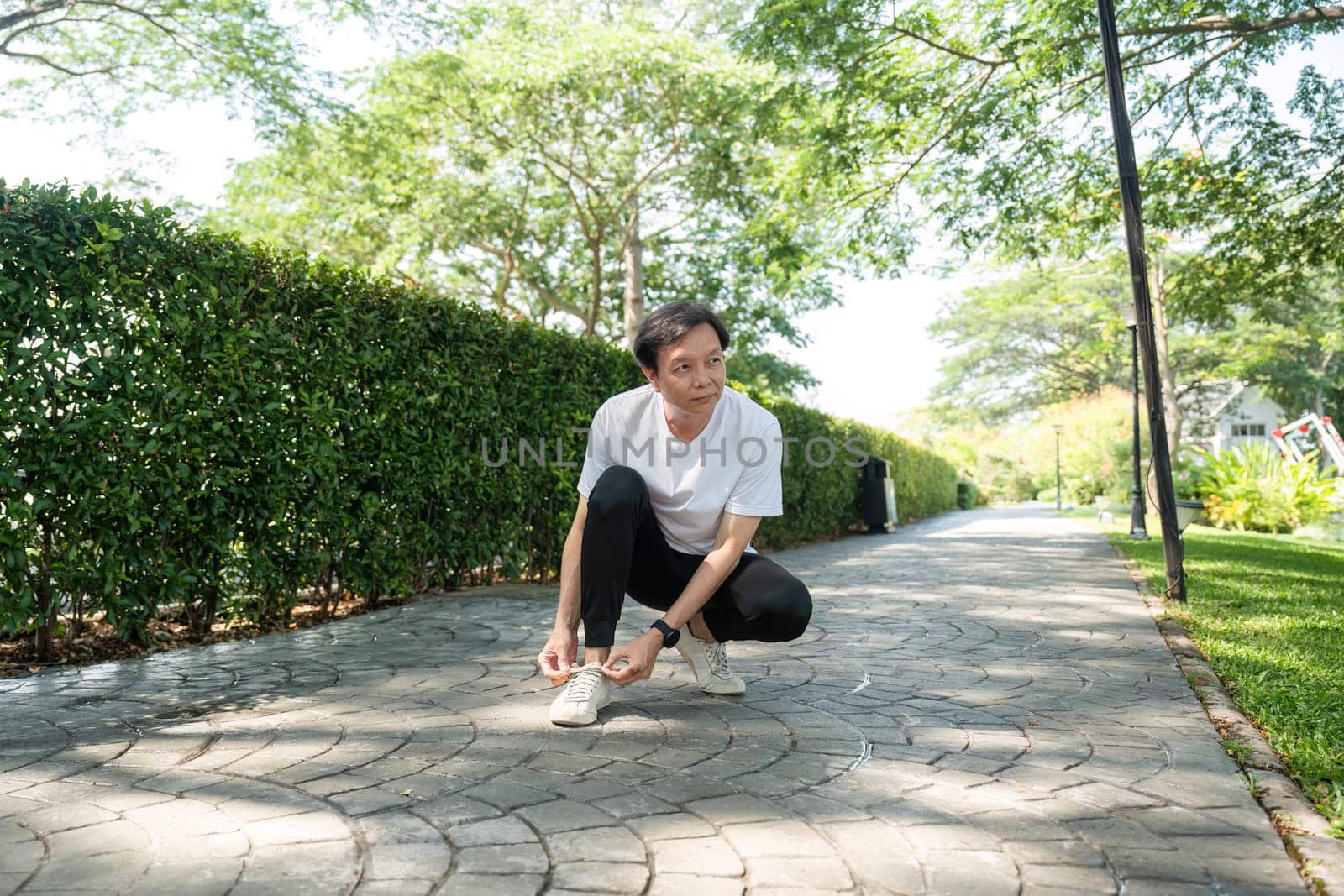 An elderly man checks his smartwatch in a park, emphasizing wellness and fitness tracking.