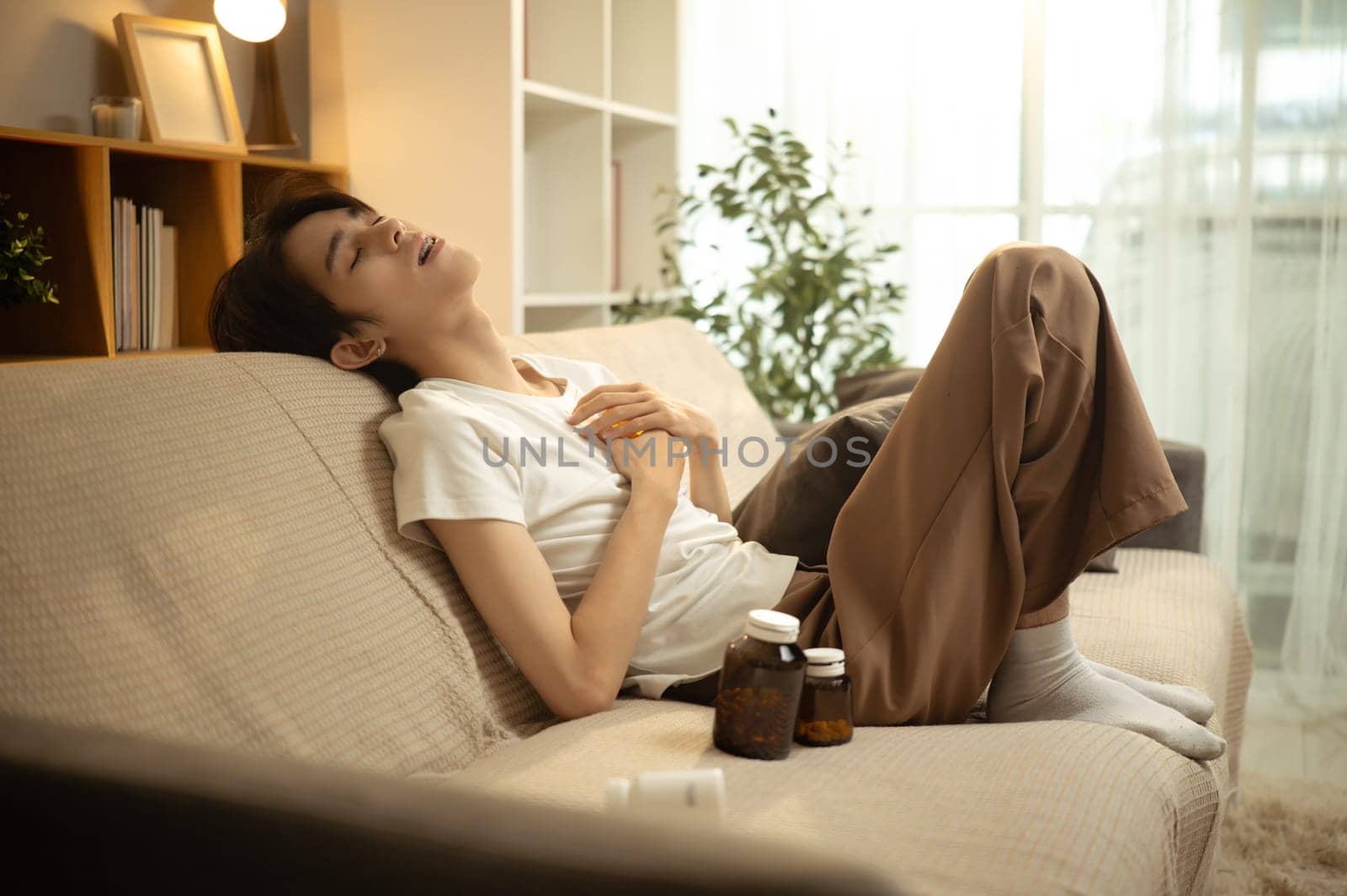 Sad man in casual clothes slumped on sofa expressing emotional burnout and despair at home..