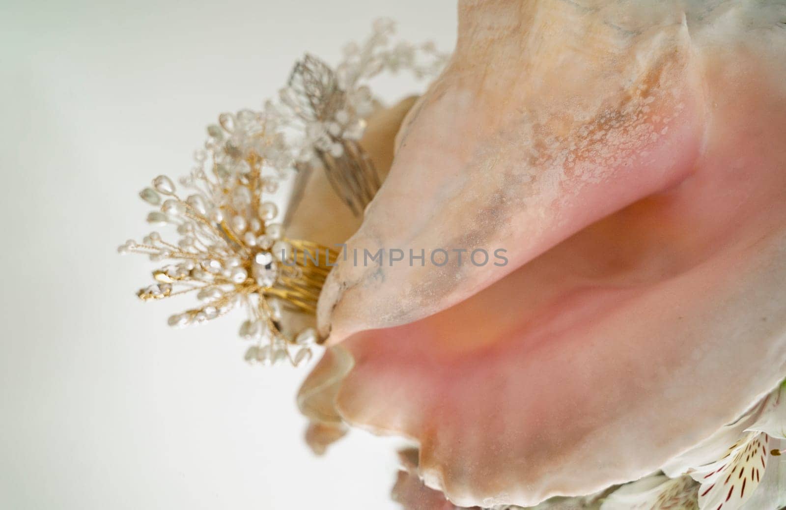 Large soft pink sea shell and hair ornaments made of small pearls. objects lie on a mirror surface. flat lay with space for text. horizontal photo