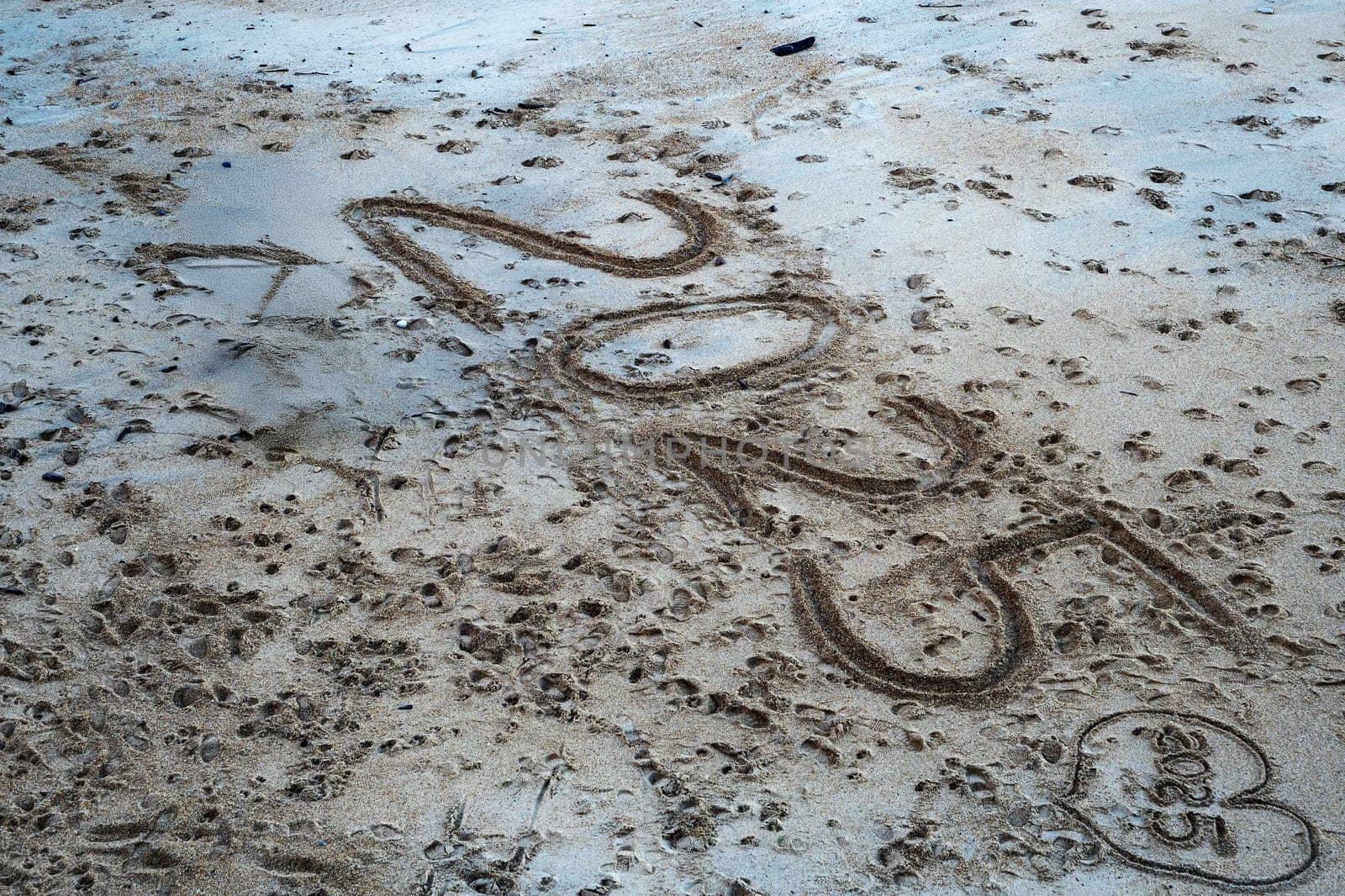 A beach with a large footprint in the sand that says "2025". The footprint is large and covers a significant portion of the sand