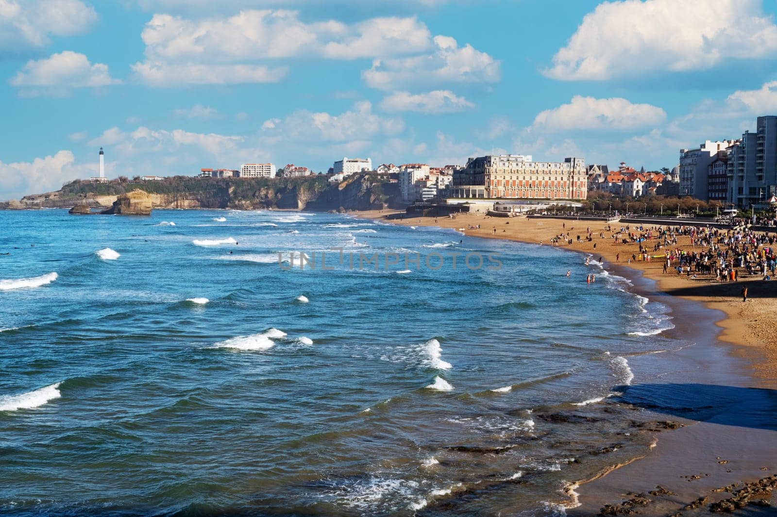 A beach with a large crowd of people and a beautiful blue ocean. Scene is peaceful and relaxing. Biarritz, France