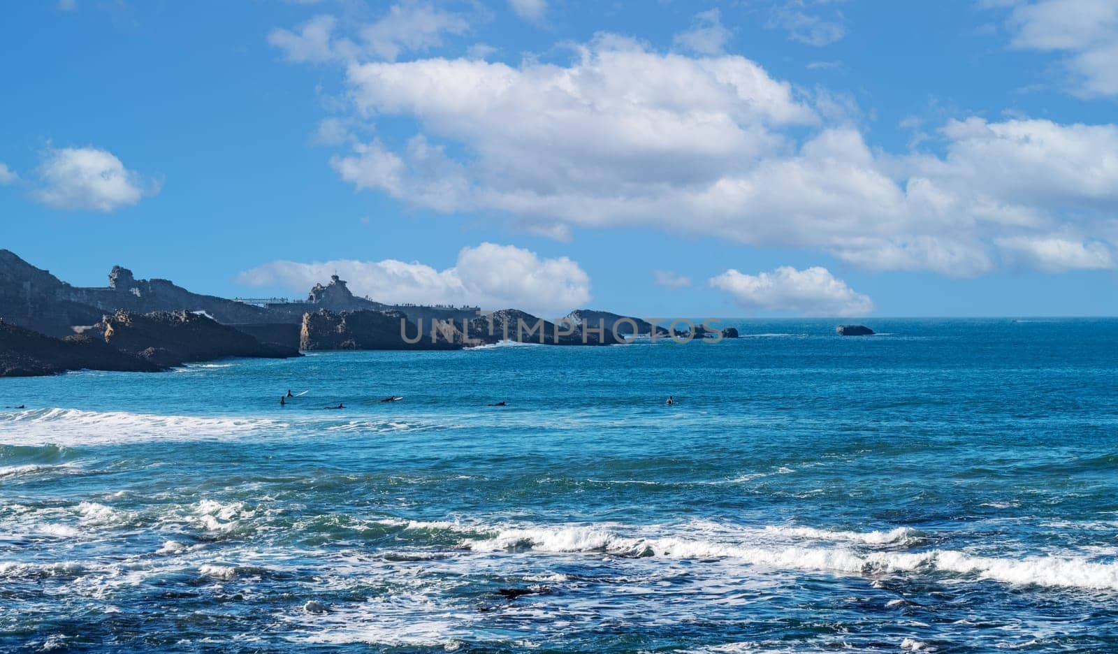 The ocean is calm and the sky is blue. The water is clear and the waves are small, Biarritz, France