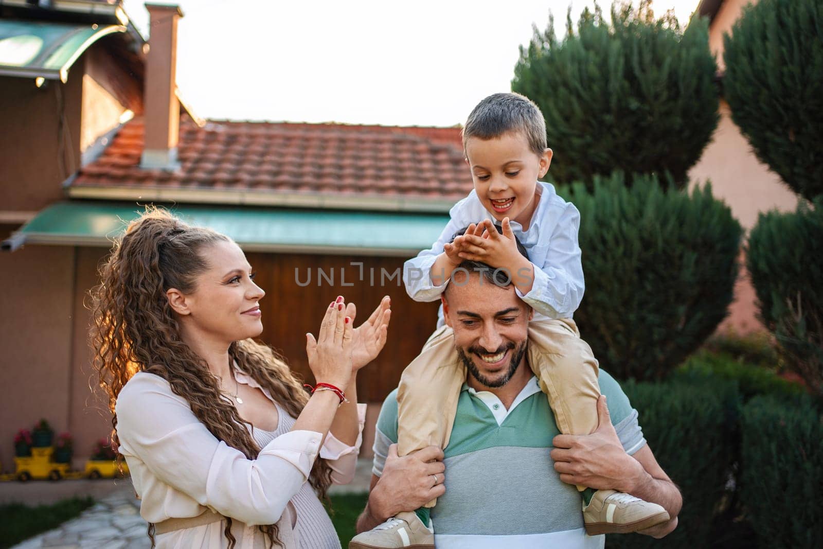 A cheerful family enjoys playful moments in a sunny garden.