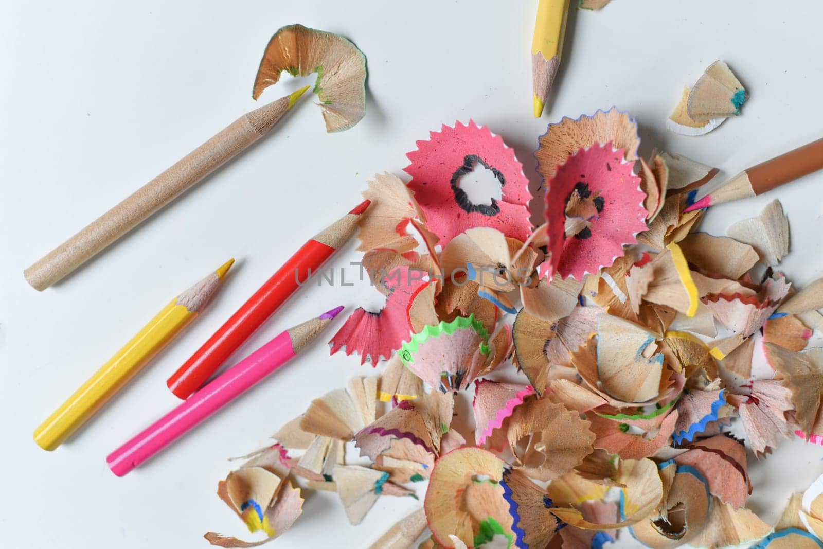 Wooden colorful pencils with sharpening shavings, on a white table