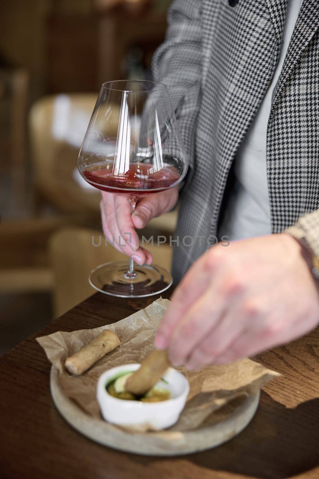 Champagne tasting in restaurant, A man holds in his hand a beautiful elegant glass with rose sparkling wine, He eats delicious snacks and drinks pink wine. High quality photo