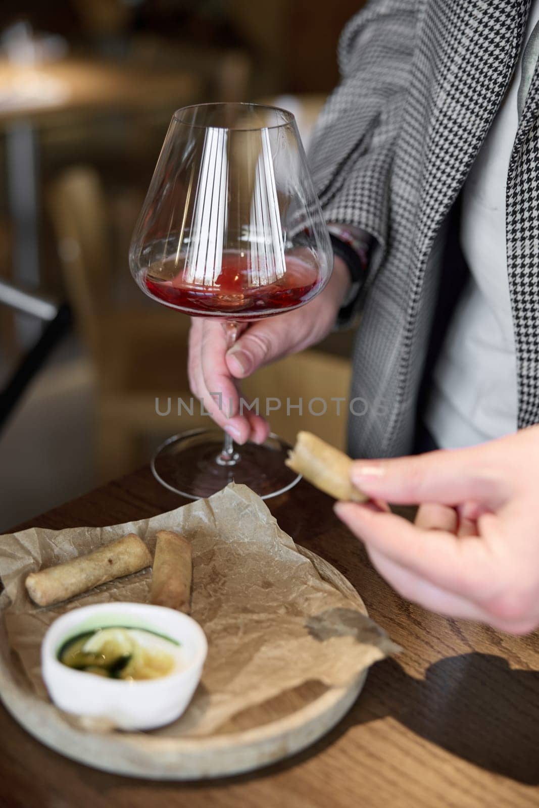 Champagne tasting in restaurant, A man holds in his hand a beautiful elegant glass with rose sparkling wine, He eats delicious snacks and drinks pink wine. High quality photo