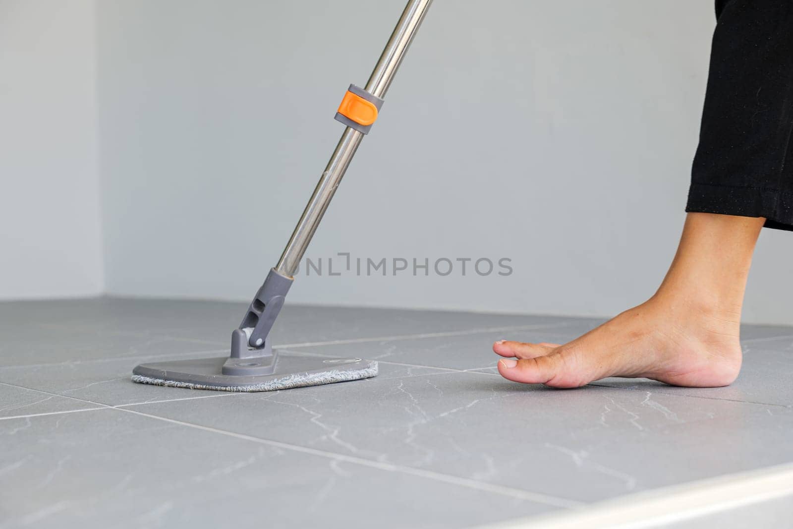 Woman mops the indoor floor, cleaning the front area of her home with a mop and rag. Housewife dedicated to maintaining cleanliness. Represents professional housekeeping and house maintenance concepts