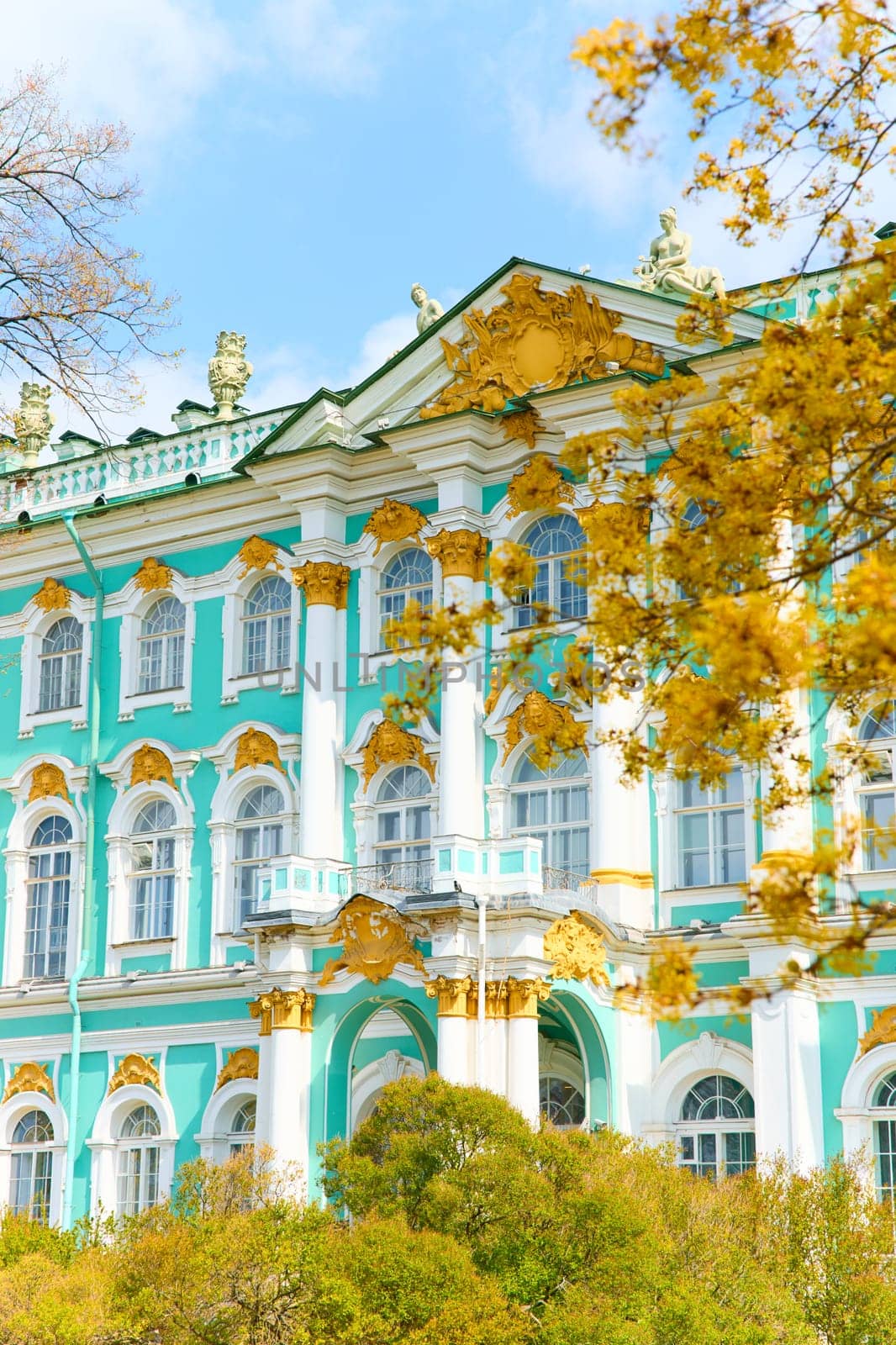 the incredibly picturesque facade of the Winter Palace through the branches of trees on a clear spring day, the heritage of Russia, the most famous landmark of St. Petersburg, the museum. High quality photo