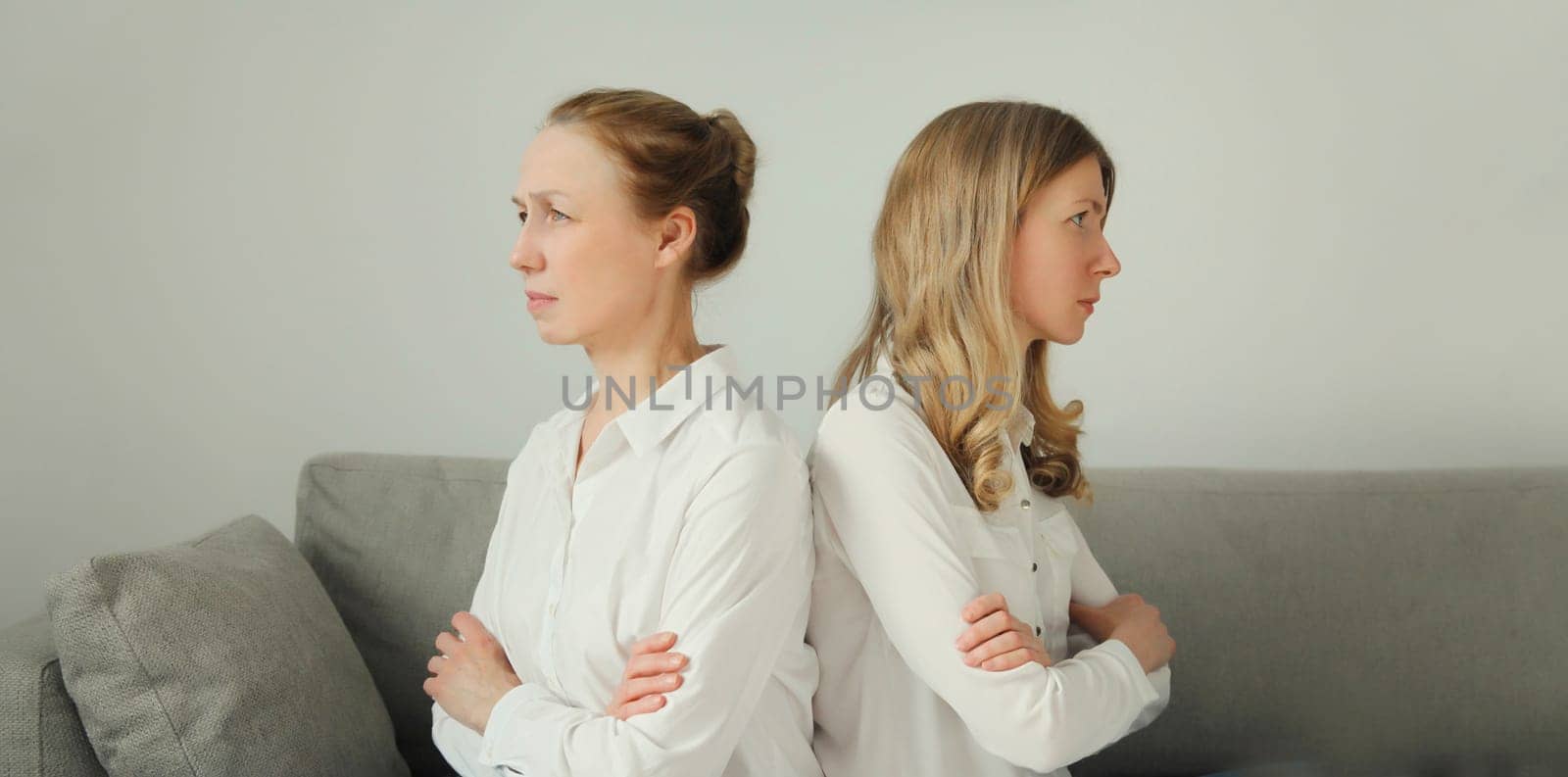 Upset offended caucasian two women, mature mother or sister and adult daughter crying together sitting on couch at home