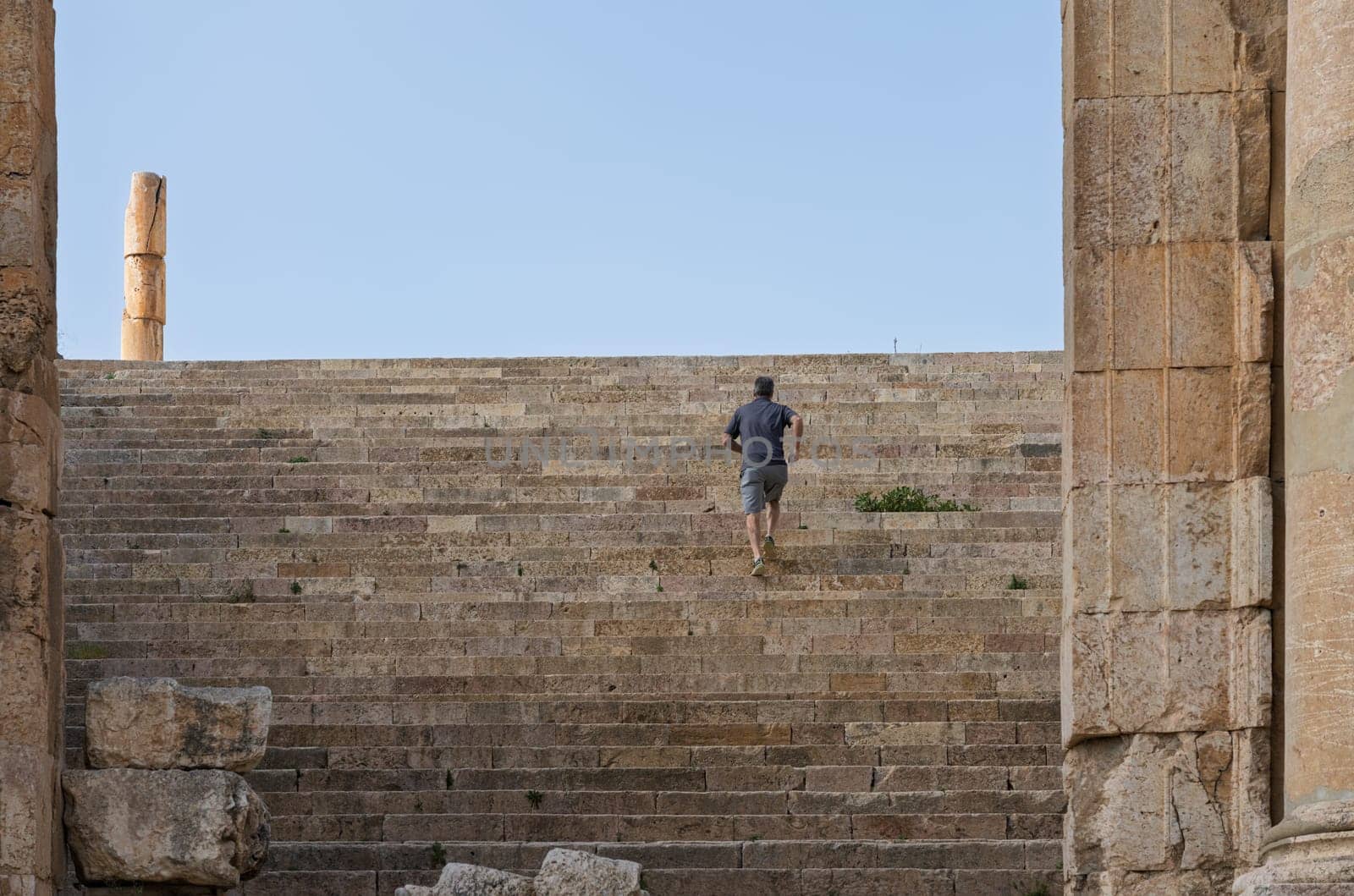 Tourist clims the staircase past the altar terrace of Sanctuary of Artemis on Cardo Maximus in Jerash, a Greco-Roman well preserved city in Jordan