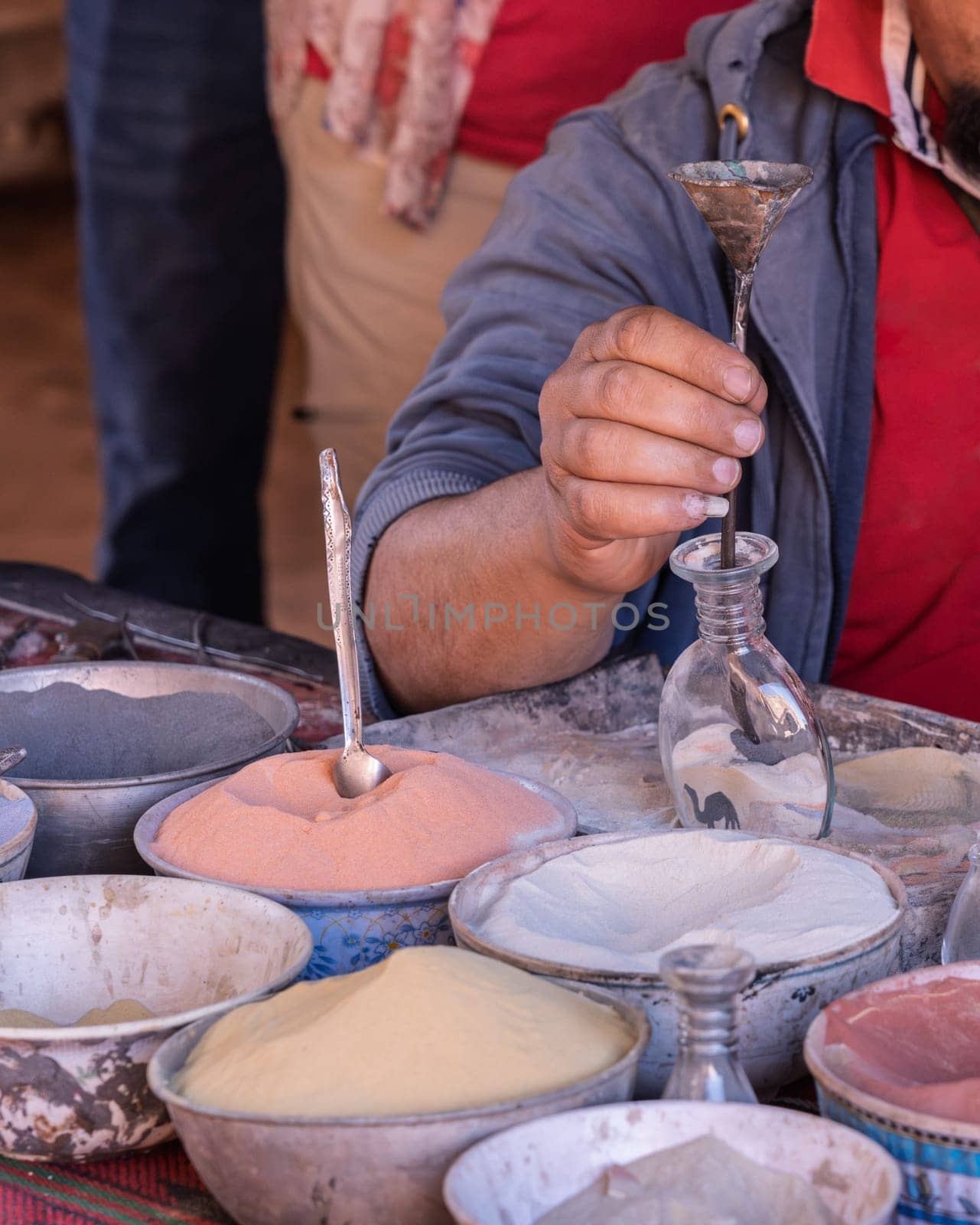 A skilled artisan meticulously crafting a colorful sand bottle souvenir in the ancient city of Petra
