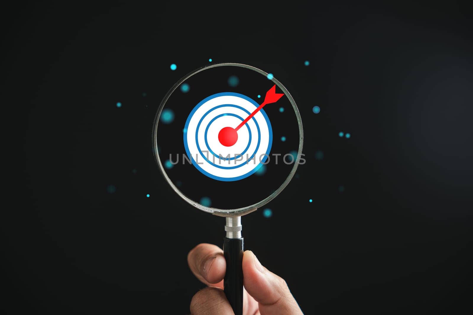 A magnifier glass highlights target board for focused business objectives, against a background with copy space. It represents the concepts of search, goal achievement, strategy, and marketing success