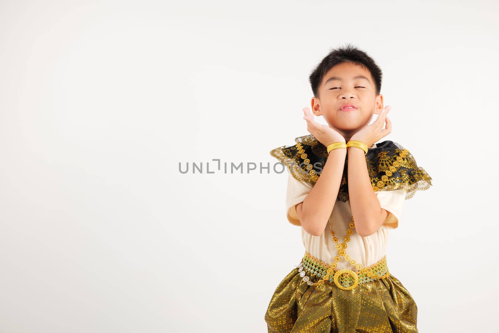 Portrait Thailand kid boy smiling traditional Thai dress costume raises her fists in celebration of her success, studio isolated white background, primary child saying yes with excitement winning