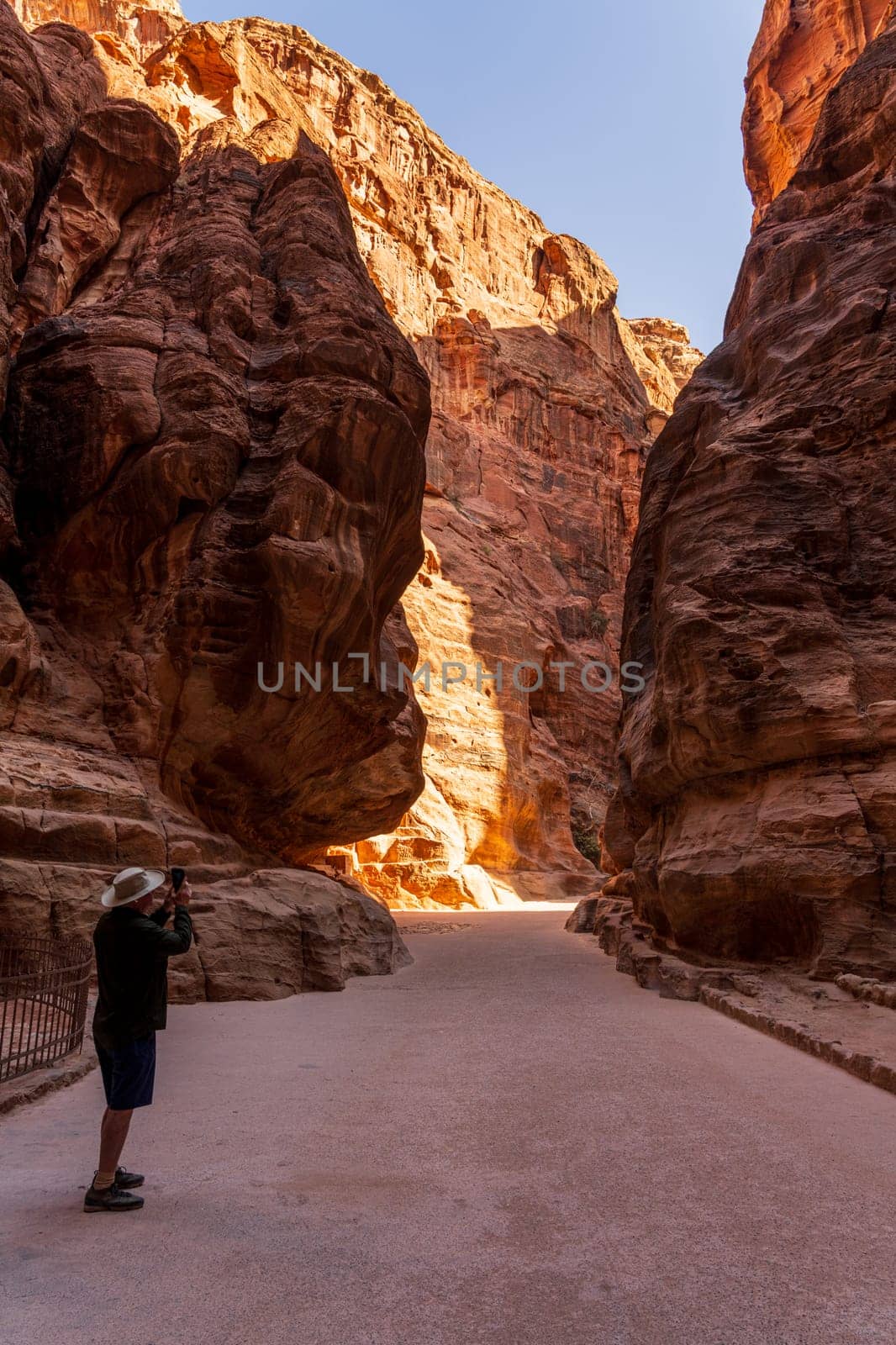 Tourists provide scale to the massive narrow gorge of the Siq entering Petra in Jordan
