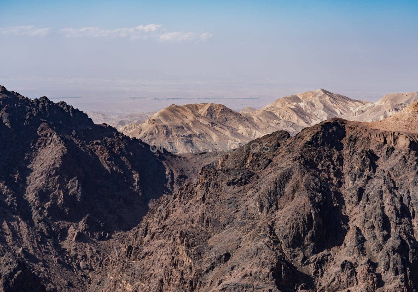 View from the top of the trail to the Monastery of rocky mountain range and gorges with Wadi Araba desert in distance