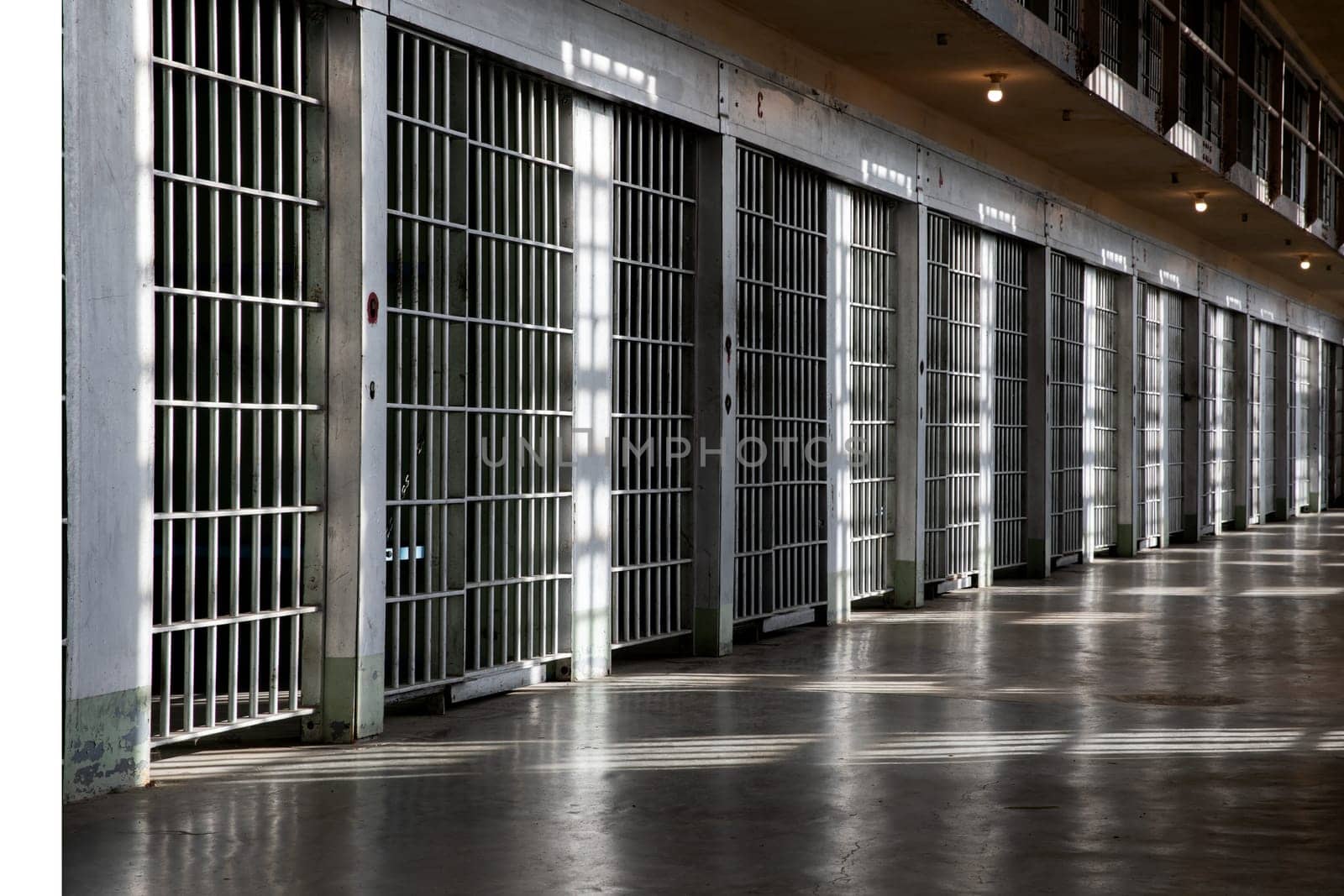 A long hallway with many bars on the windows. The bars are white and the windows are clear