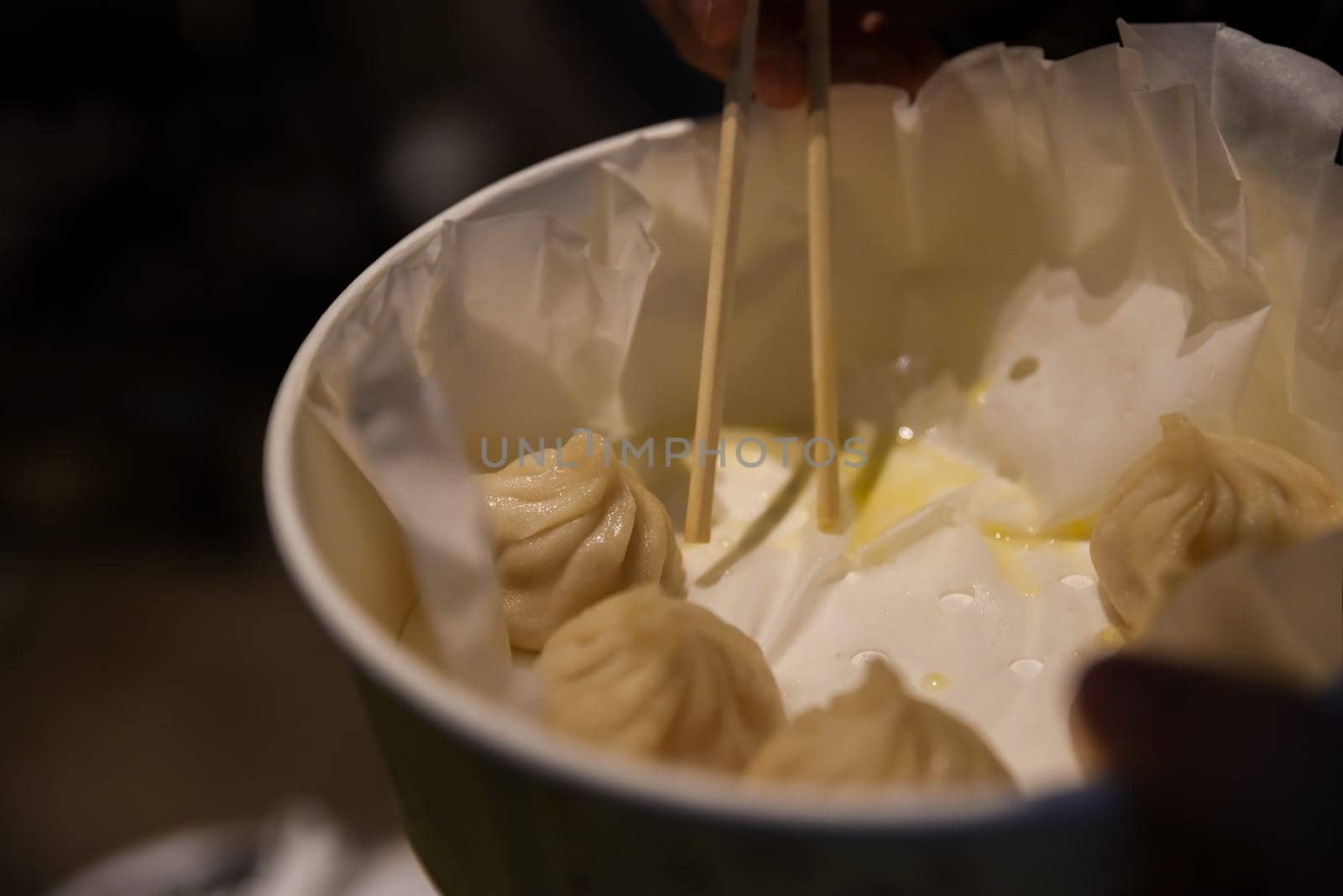 Close-up of steamed Chinese dumplings with crab and pork in a take-out bowl on Yuyuan Old Street, ready to eat with chopsticks in Shanghai, China
