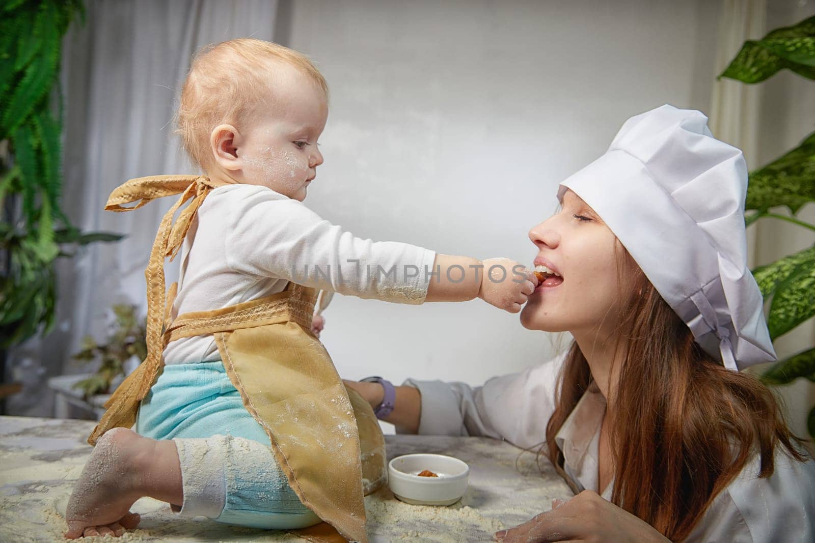 A mother and daughter joyfully engage in a flour-filled moment, creating memories in a cozy kitchen setting.