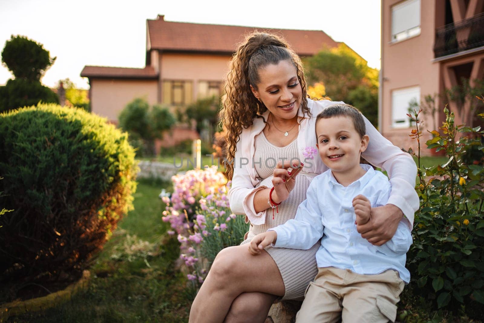 A mother delights in playful interaction with her son outdoors.
