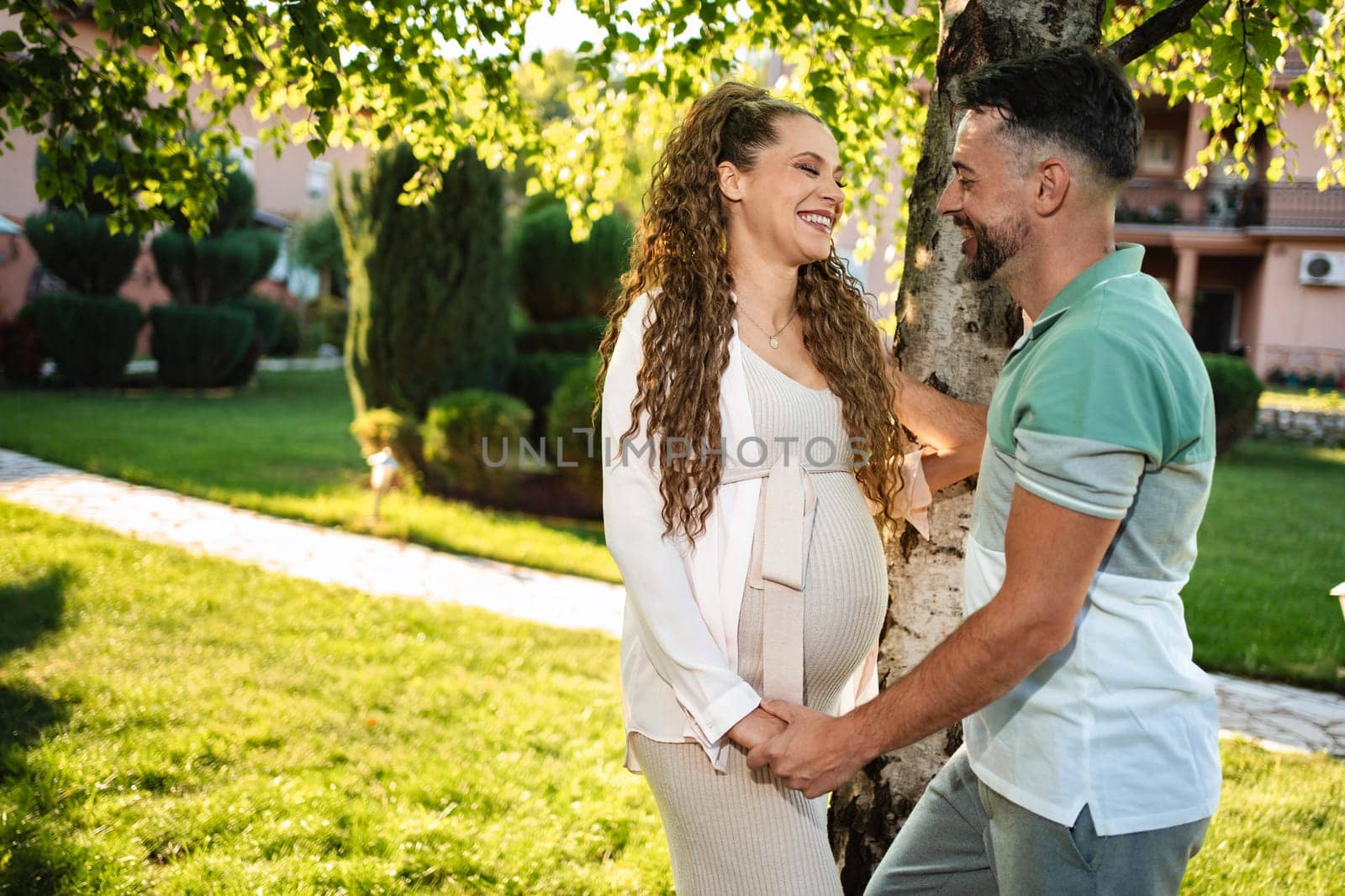 Two smiling individuals share a sweet moment outdoors.