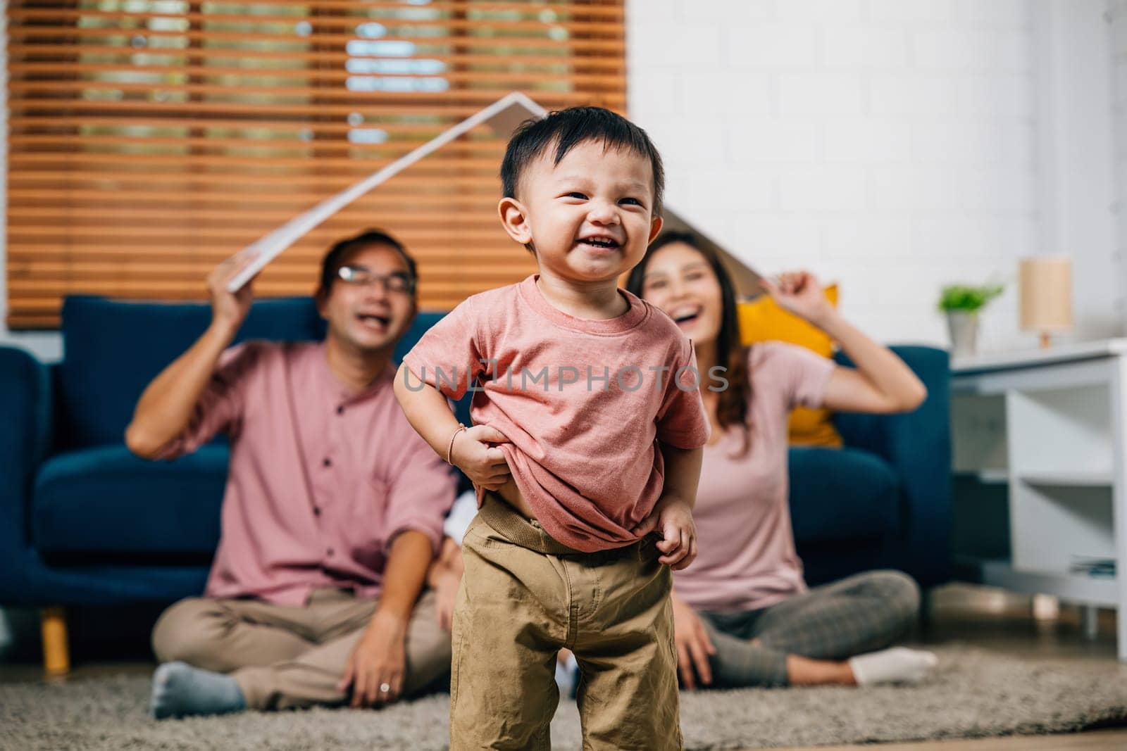 In their new home a loving family sits on the sofa holding a cardboard roof mockup representing security and joy during their home relocation. The answer is family togetherness and planning.