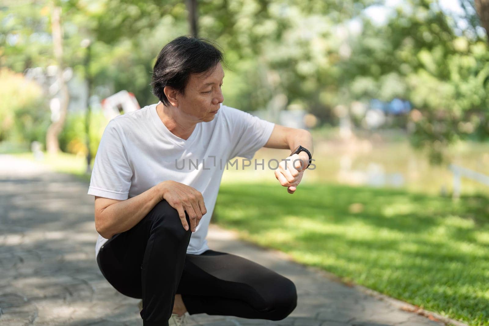 A middle-aged man monitors his fitness progress on a smartwatch while enjoying a day in the park, promoting wellness and active lifestyle.