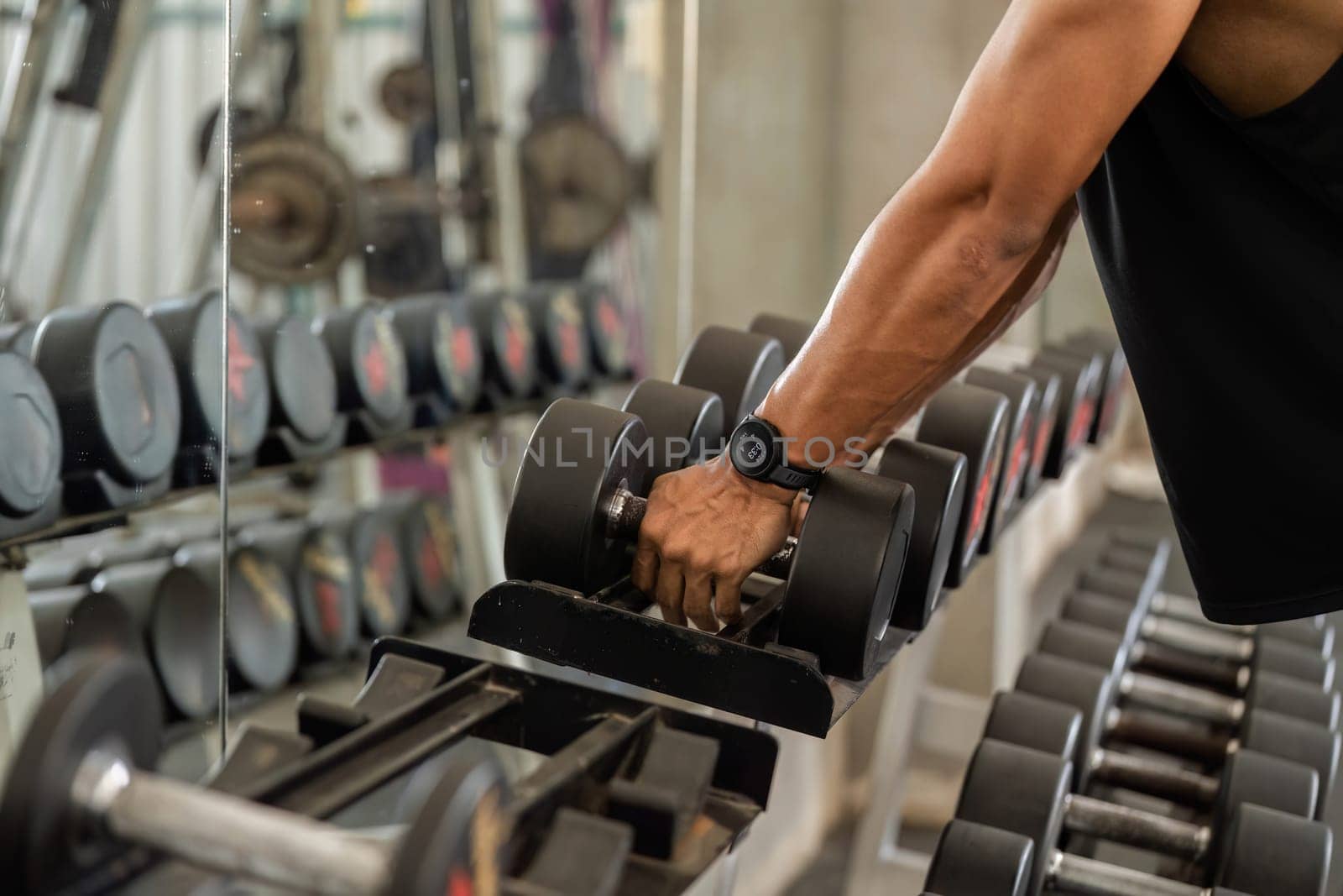 A focused man grips a dumbbell in the gym, demonstrating strength and commitment to fitness training.