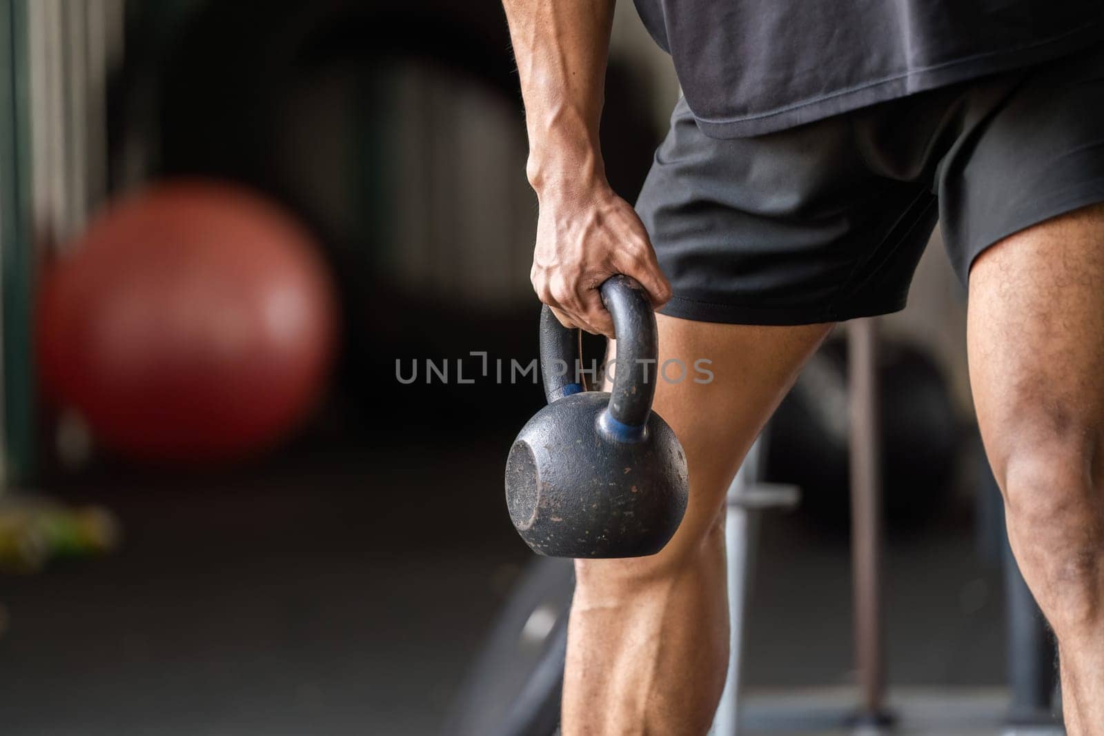A fitness enthusiast lifts a kettlebell, showcasing strength and focus during a workout in a gym environment.