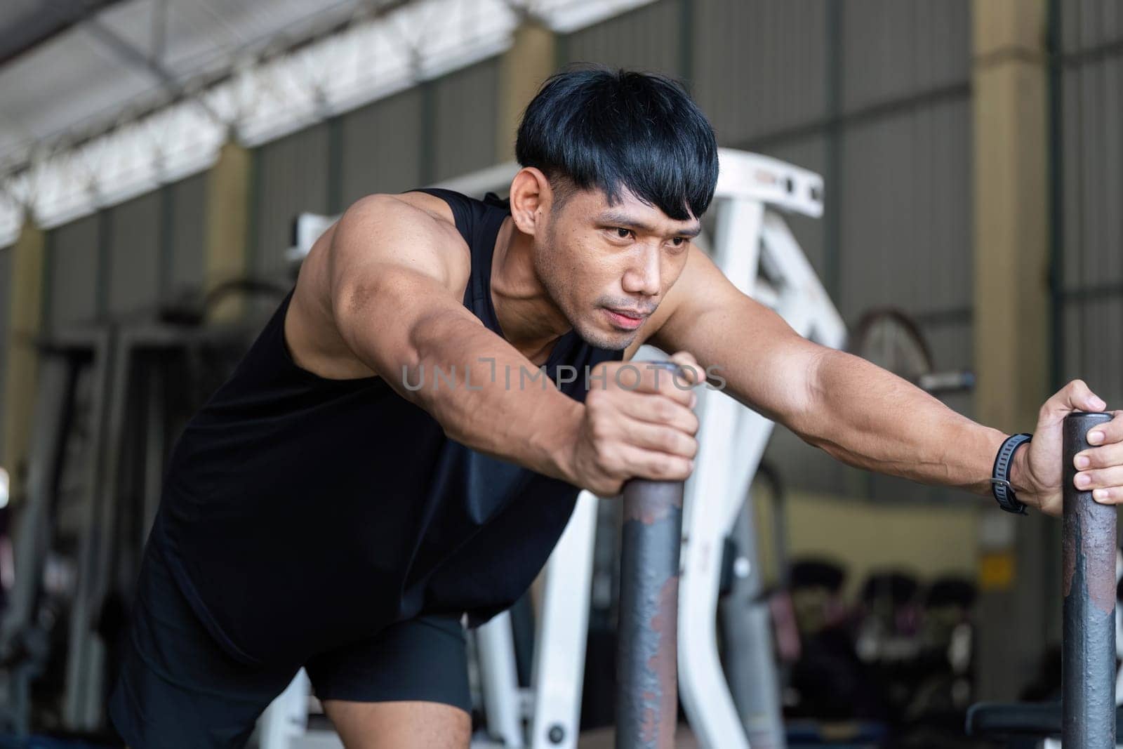 A dedicated male athlete leans forward on gym equipment, demonstrating strength and commitment to fitness.