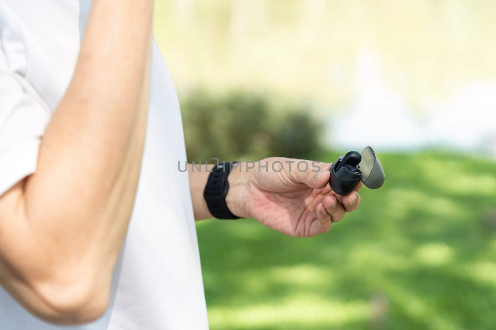 A close-up of a senior man's hand holding headphones, reflecting the connection between music and wellness.