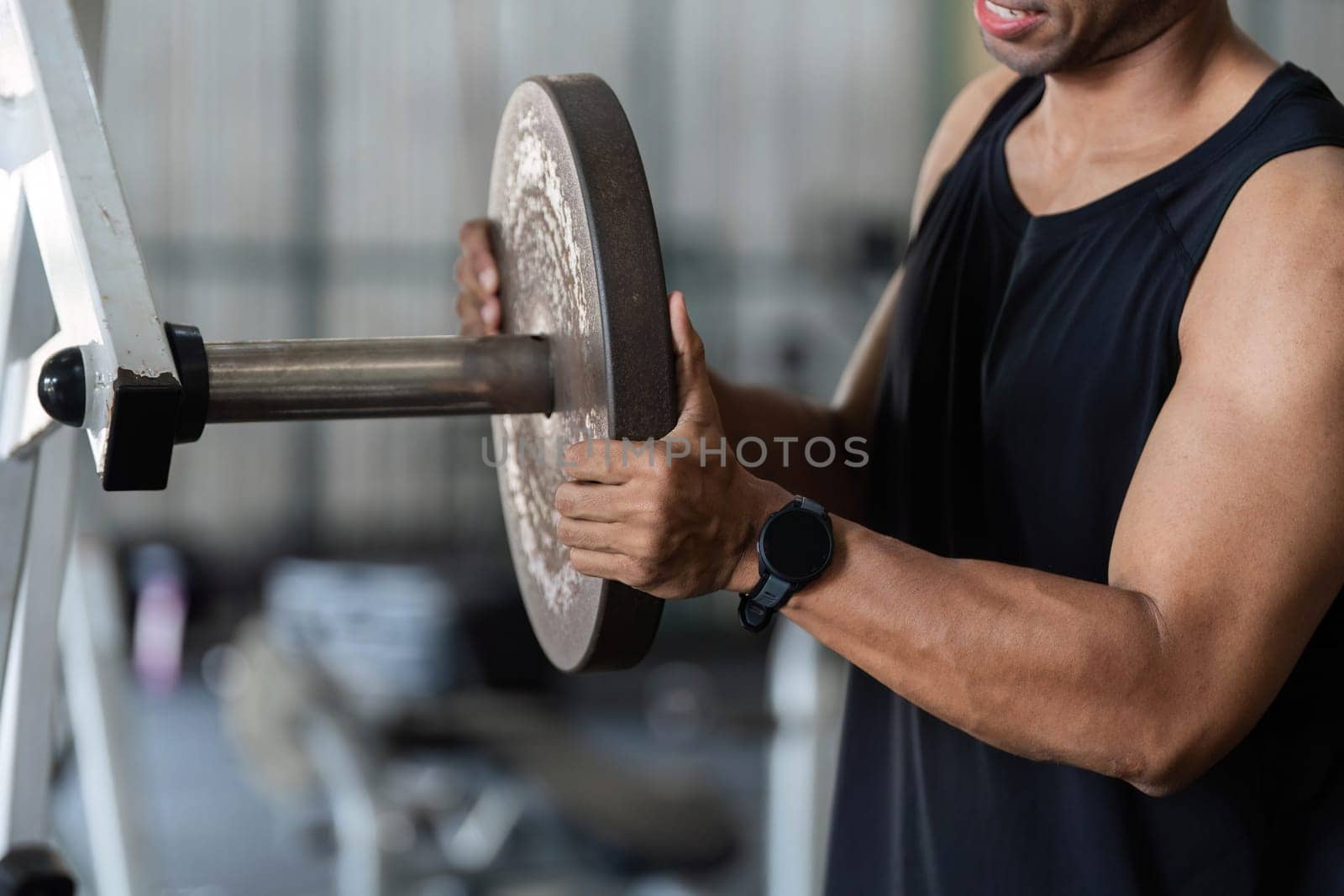 A young man prepares to lift a weight plate, demonstrating commitment to fitness and strength training in a gym setting.