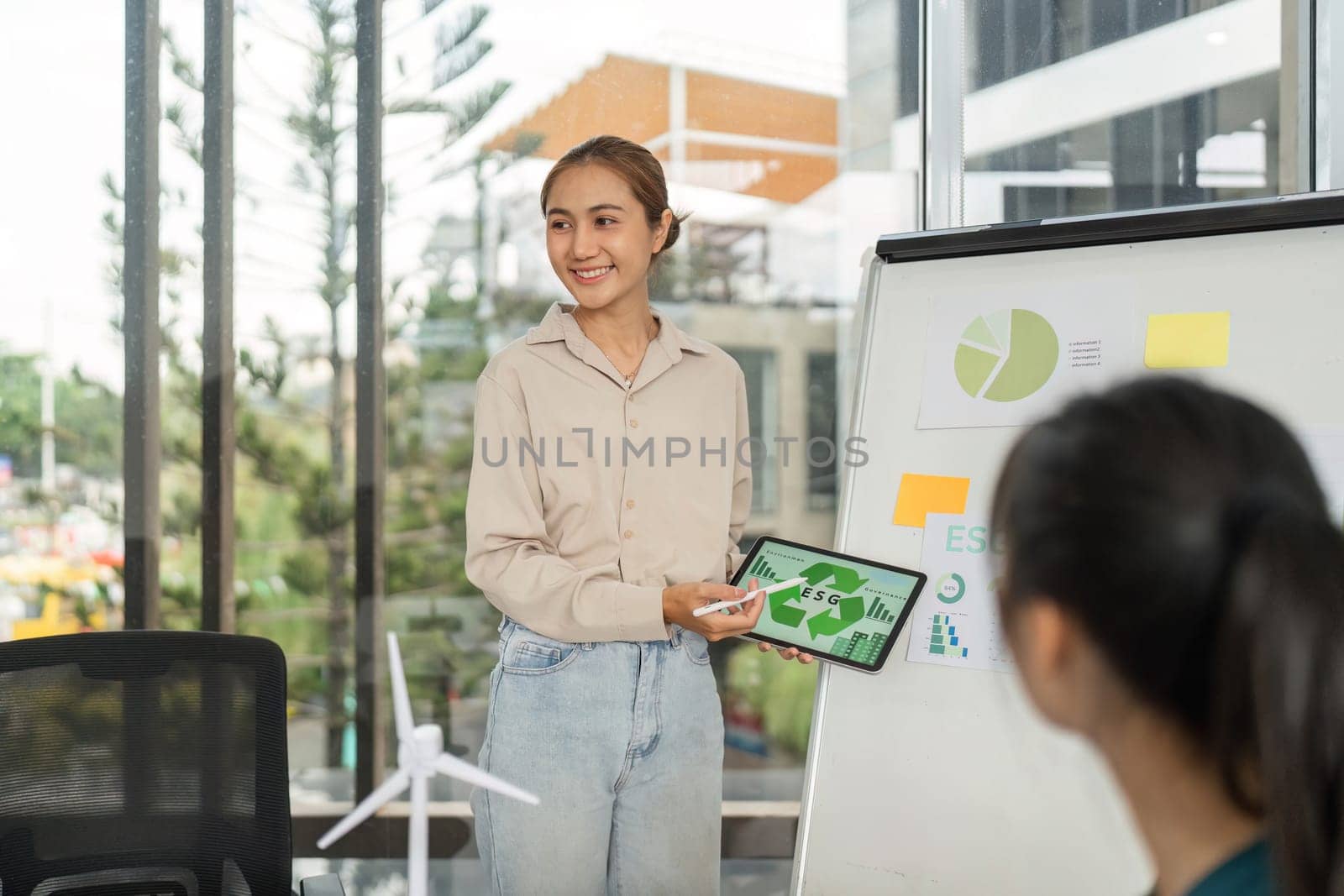 In a modern office, a woman discusses ESG strategies with her team, promoting sustainability and corporate responsibility.