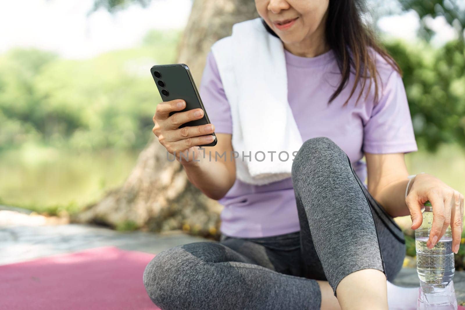 A woman engages with her smartphone during a wellness break in nature, promoting mindfulness and relaxation.