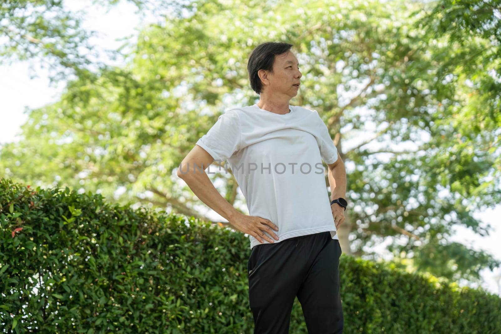 An elderly man stretches his arms in a park, promoting wellness and physical fitness. Emphasizing active lifestyle and health.