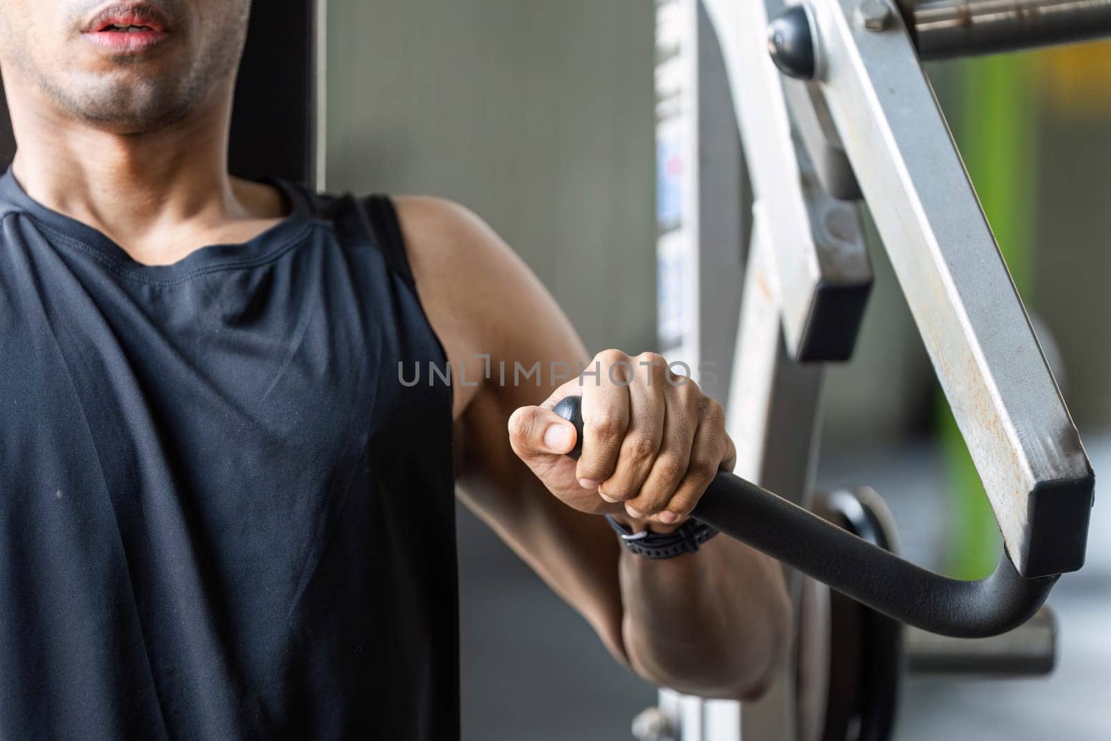 A focused male athlete engages in strength training using a machine, showcasing dedication and fitness.