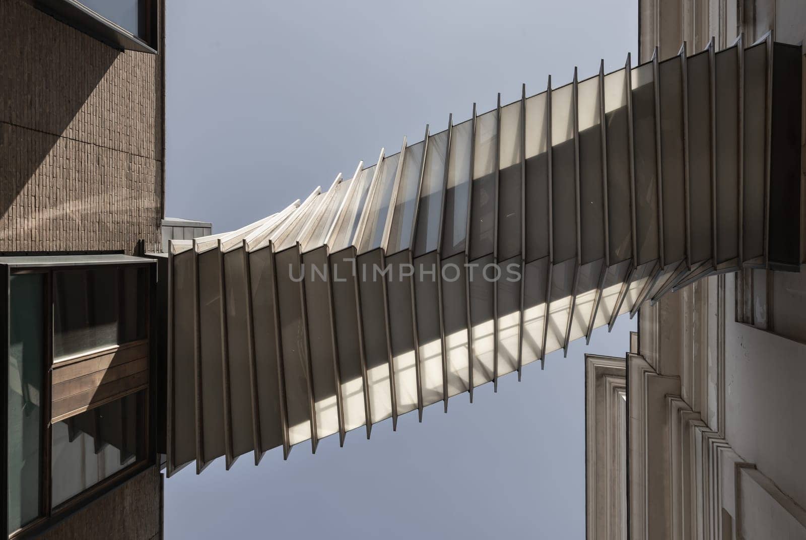 London, UK - May 13, 2025 - Looking up of The futuristic modern of Twisted sky bridge connecting Royal opera house to Royal ballet school in Covent garden. Exterior architectural design of Bridge of Aspiration with sky background, Stunning of Passageway between buildings, use it as your Wallpaper, Poster and Copy space, Selective focus.