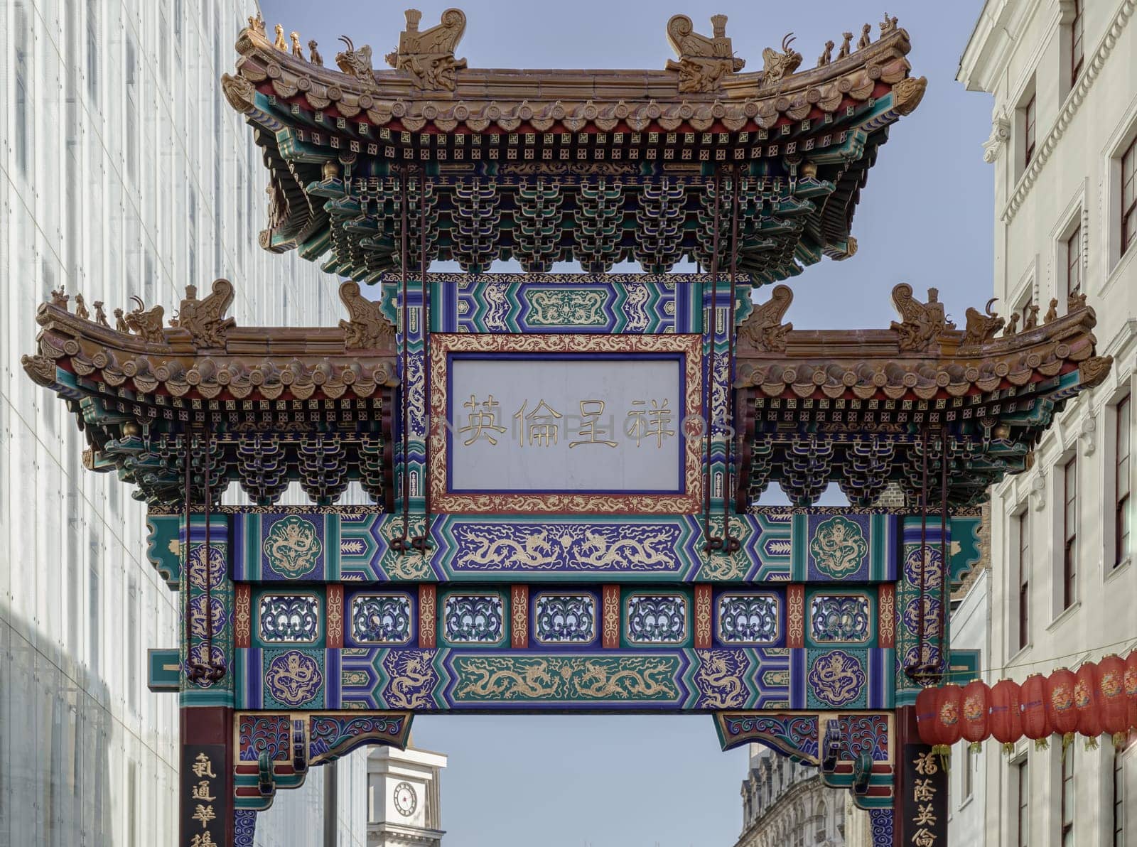 London, UK - May 13, 2025 - View of London Chinatown entrance gate in traditional chinese design with glazed yellow tiles, a golden dragon, painted panels, two white jade plaques. The Chinese text translates "Peace and Prosperity (Zhong guo tai ping) to Chinatown". use it as your Wallpaper, Poster and Space for text, Selective focus.