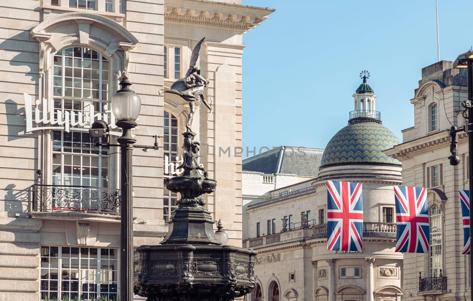 London, UK - May 13, 2025 - The Statue of Eros is The Greek god anteros (the Greek God of love)​ that sits atop of the Shaftesbury memorial fountain with Lillywhites and The Plaza Theatre building (Apollo cinema) in the background. a cast aluminium sculpture with winged poised in Piccadilly circus. use it as your Wallpaper, Poster and Copy space, Selective focus.