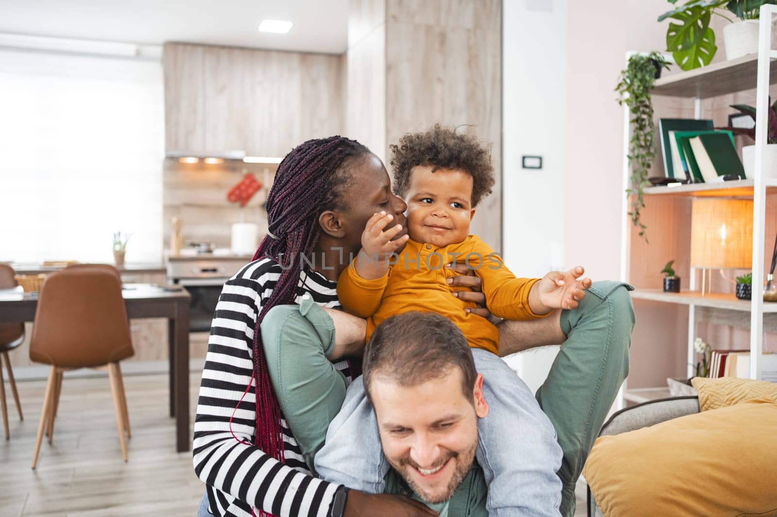 A mother and father playfully interact with their young child indoors.