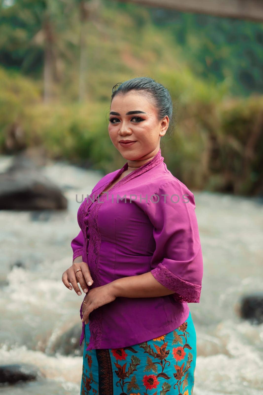 Asian woman standing in front of the river while wearing a purple dress with beautiful makeup and river in the background inside the village