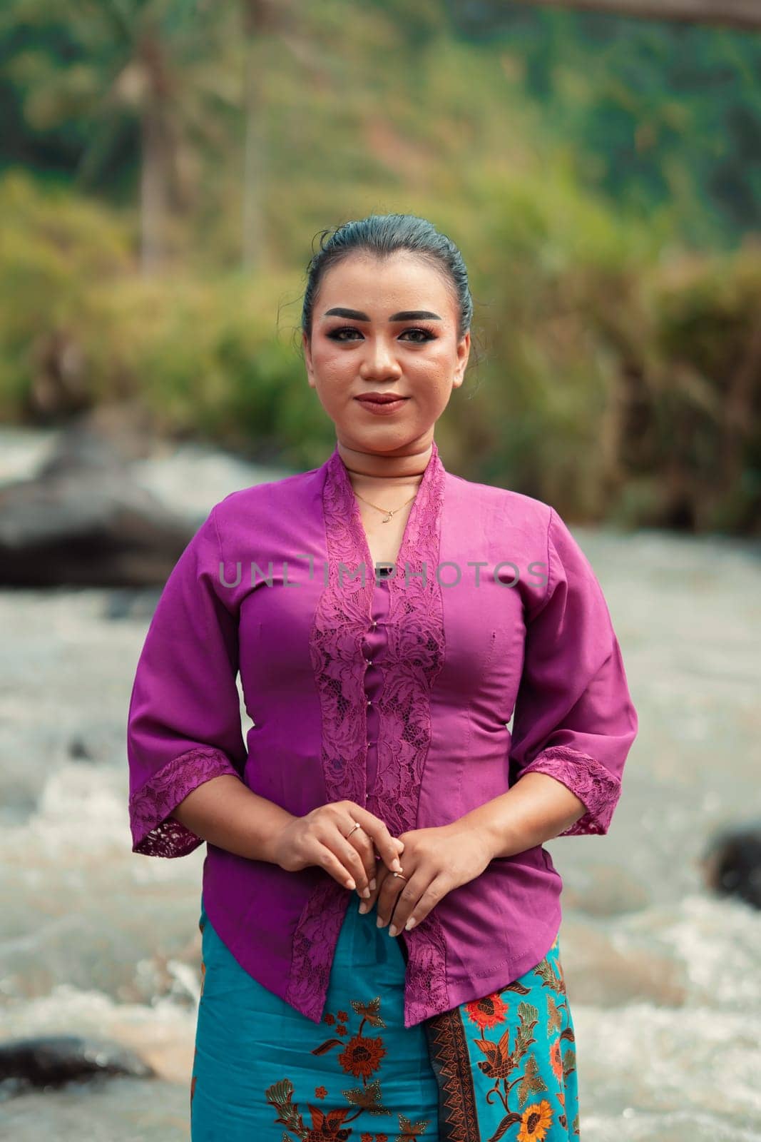 Asian woman standing in front of the river while wearing a purple dress with beautiful makeup and river in the background inside the village