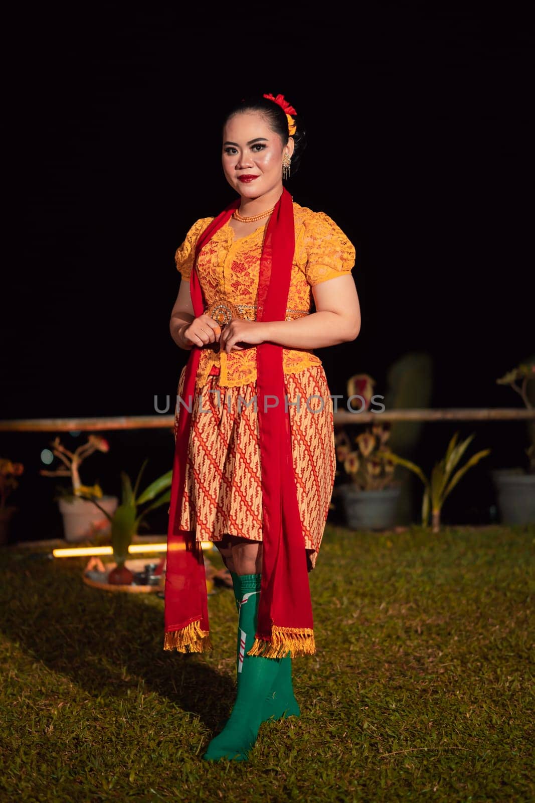 Cute Indonesian woman with red lips and a red scarf wearing a traditional Sundanese dress called kebaya inside the dance festival
