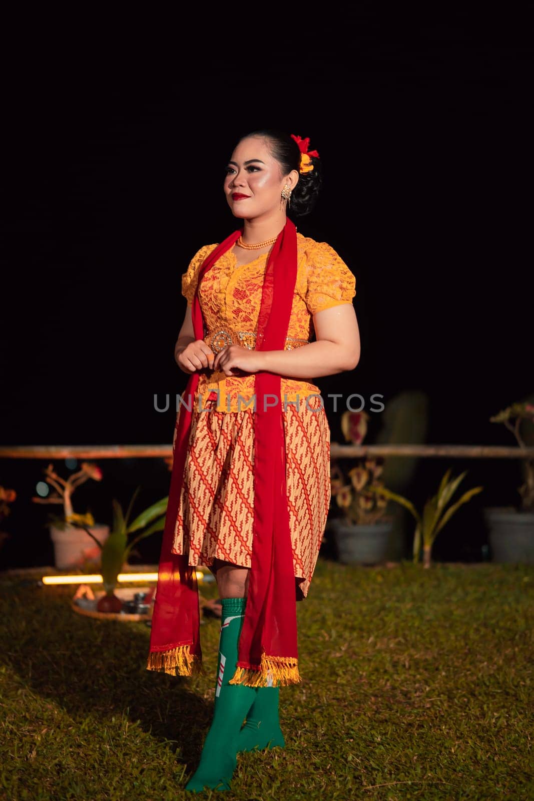 Cute Indonesian woman with red lips and a red scarf wearing a traditional Sundanese dress called kebaya inside the dance festival