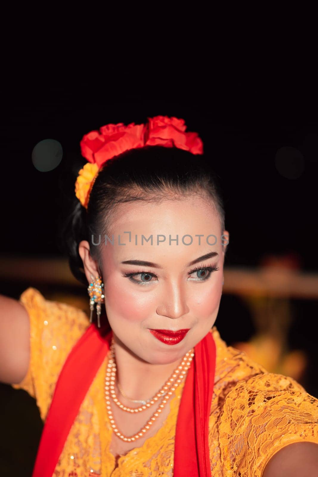 Beautiful Asian woman with makeup and flower accessories on her hair while wearing gold jewelry in the night