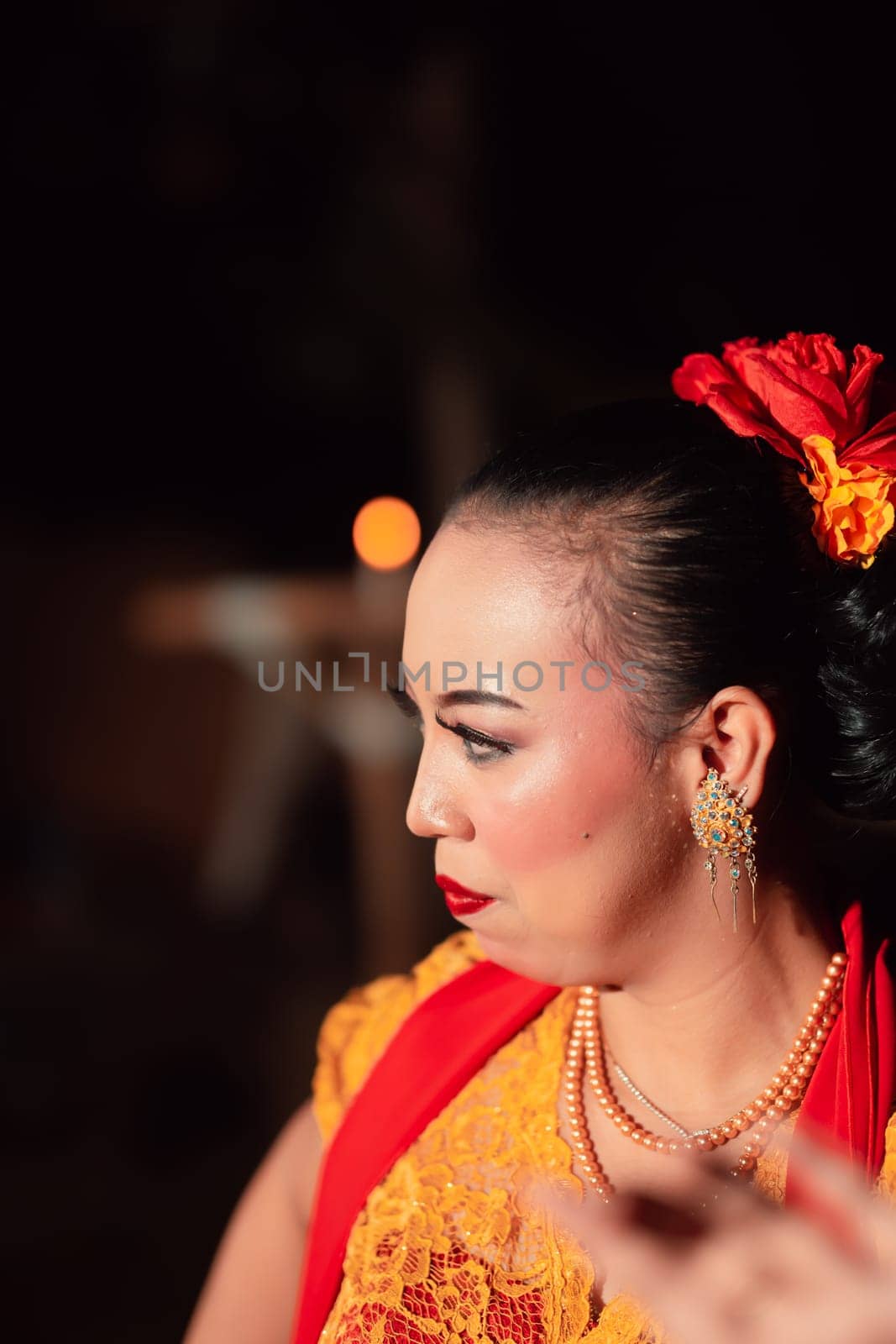 Beautiful Asian woman with makeup and flower accessories on her hair while wearing gold jewelry in the night