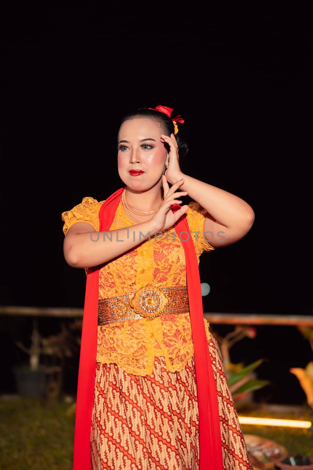Beautiful Javanese woman with a golden necklace on her neck and golden belt on a yellow dress on their body during the dance performance