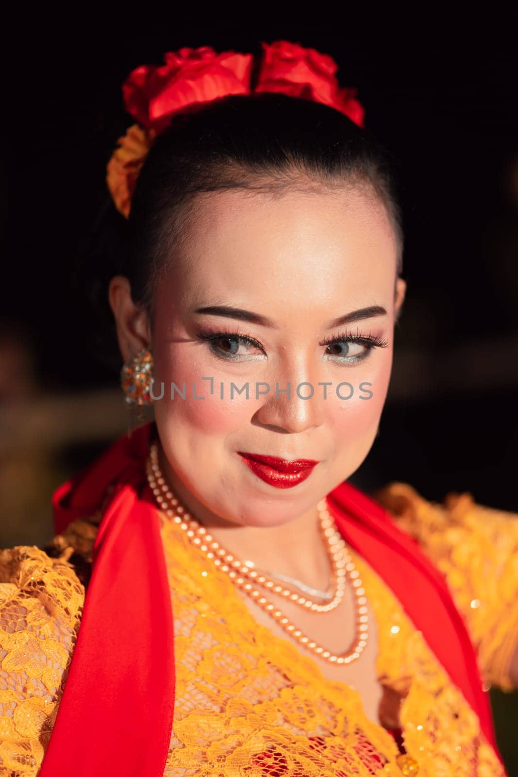 Beautiful Asian woman with makeup and flower accessories on her hair while wearing gold jewelry in the night