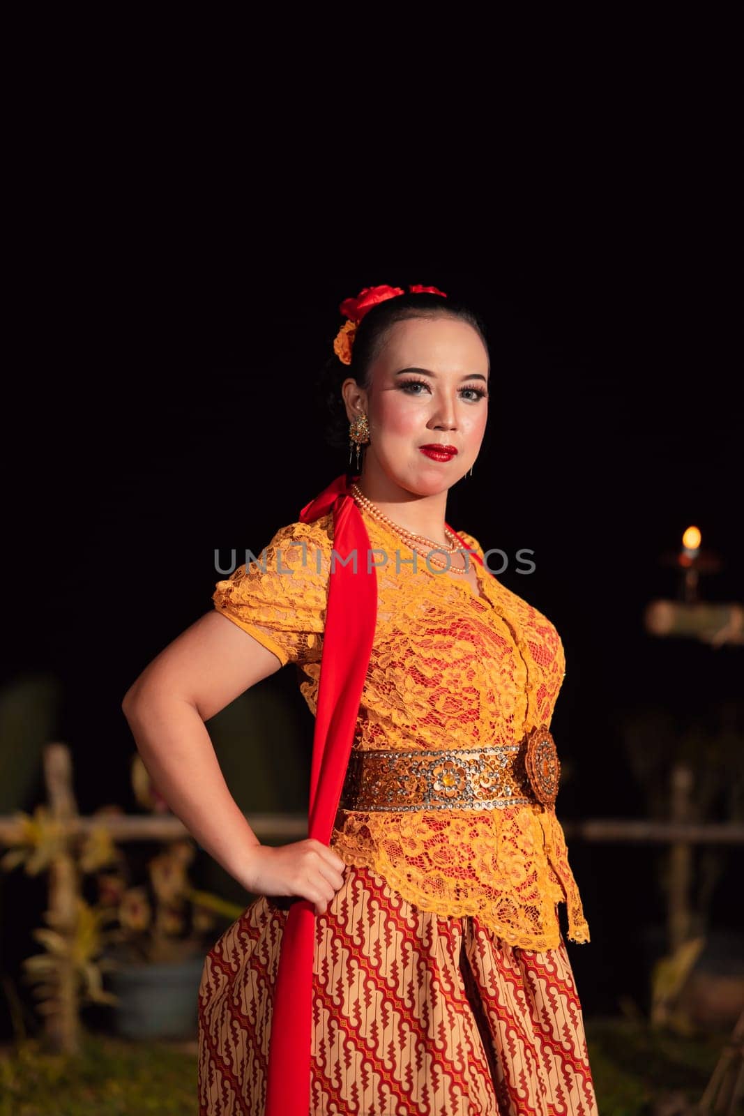 Sexy Balinese woman with makeup while wearing an orange dress called kebaya posing bravely after dancing in the village