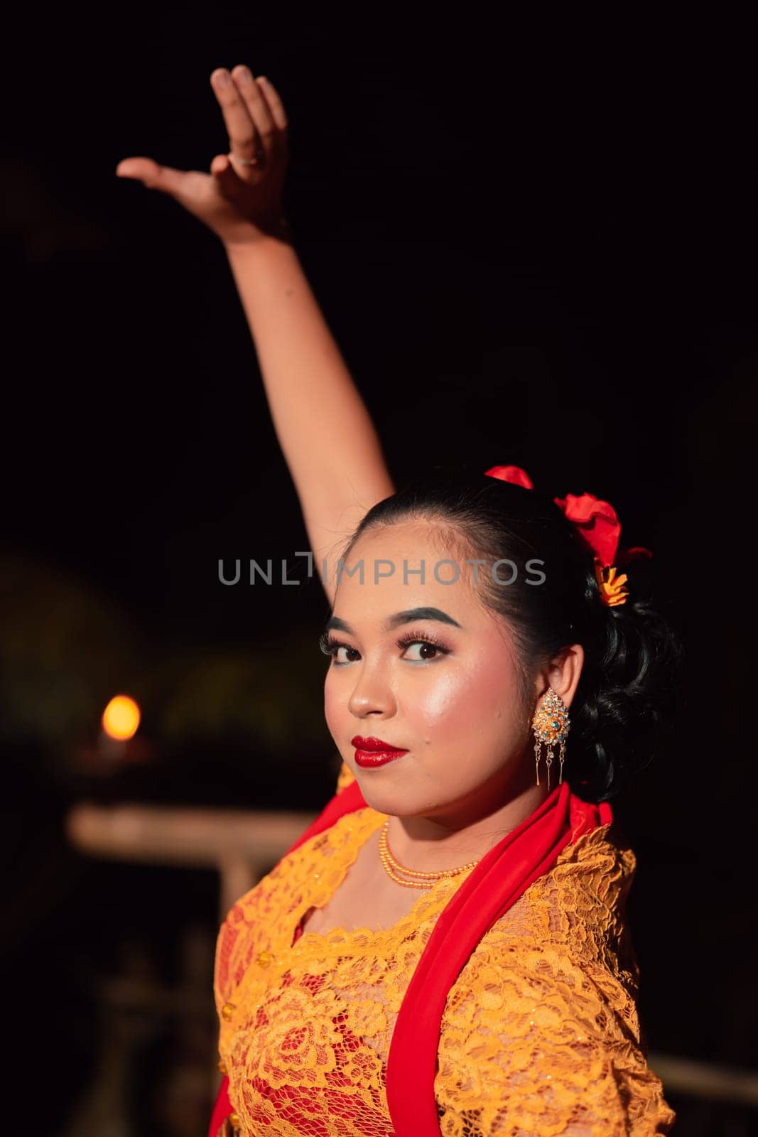 The beautiful closeup face of a Javanese woman with make-up at a traditional dance performance while wearing a yellow costume in the village